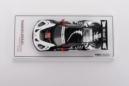 A pre-order listing for a TSM Model Porsche 911 Carrera S 877 scale diecast model car. The car is shown inside its clear plastic blister packaging, featuring a black and white livery with red accents, including a prominent 'Mobil 1' sponsor logo.